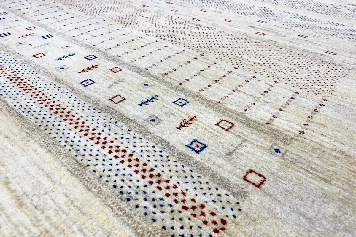 Gabbeh rug detail view: fine embroidered patterns in blue, red, and beige along a stripe