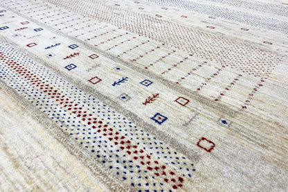Gabbeh rug detail view: fine embroidered patterns in blue, red, and beige along a stripe