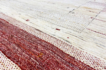 Gabbeh rug close-up: beige textured weave with a dark red horizontal stripe