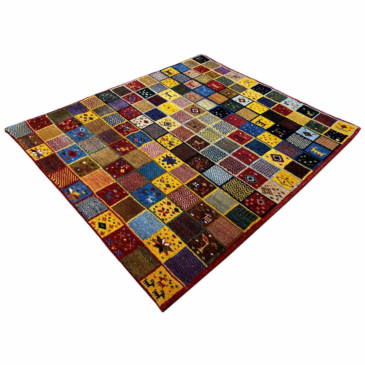Gabbeh rug (144x125 cm) with a large patchwork design in red, yellow, blue, black, and brown.
