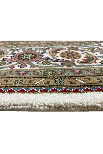 Indo Tabriz rug: close-up of the border in beige, green, and red with fringes