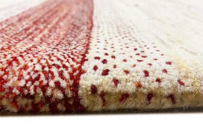 Gabbeh rug detail: pile at the edge, beige background with a reddish area