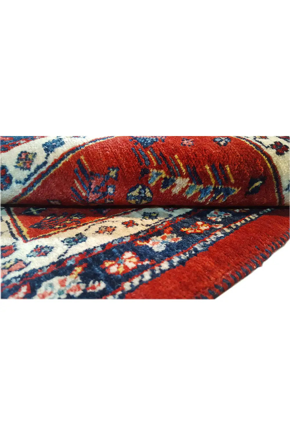 Close-up: red carpet fabric with blue-beige ornaments and visible pile texture