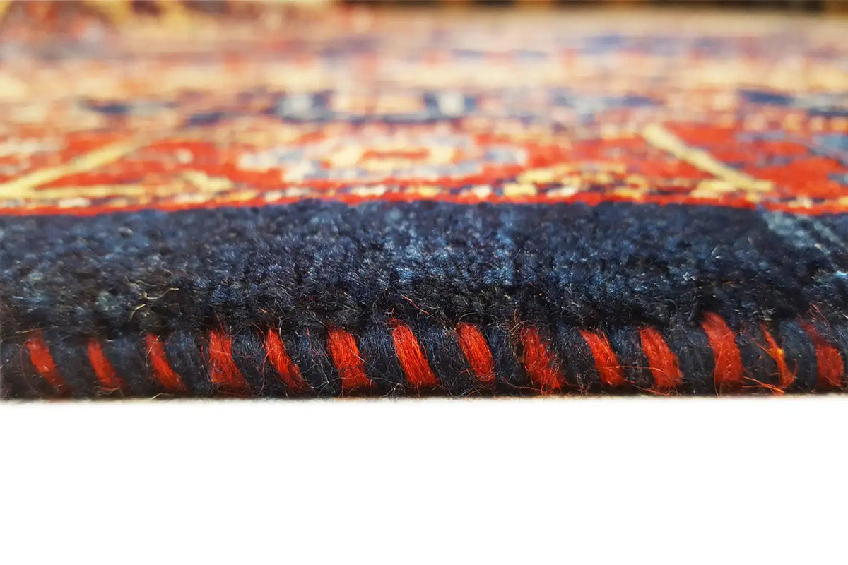 Rug edge with fringe, dark-blue pile, and red-blue patterned stripes