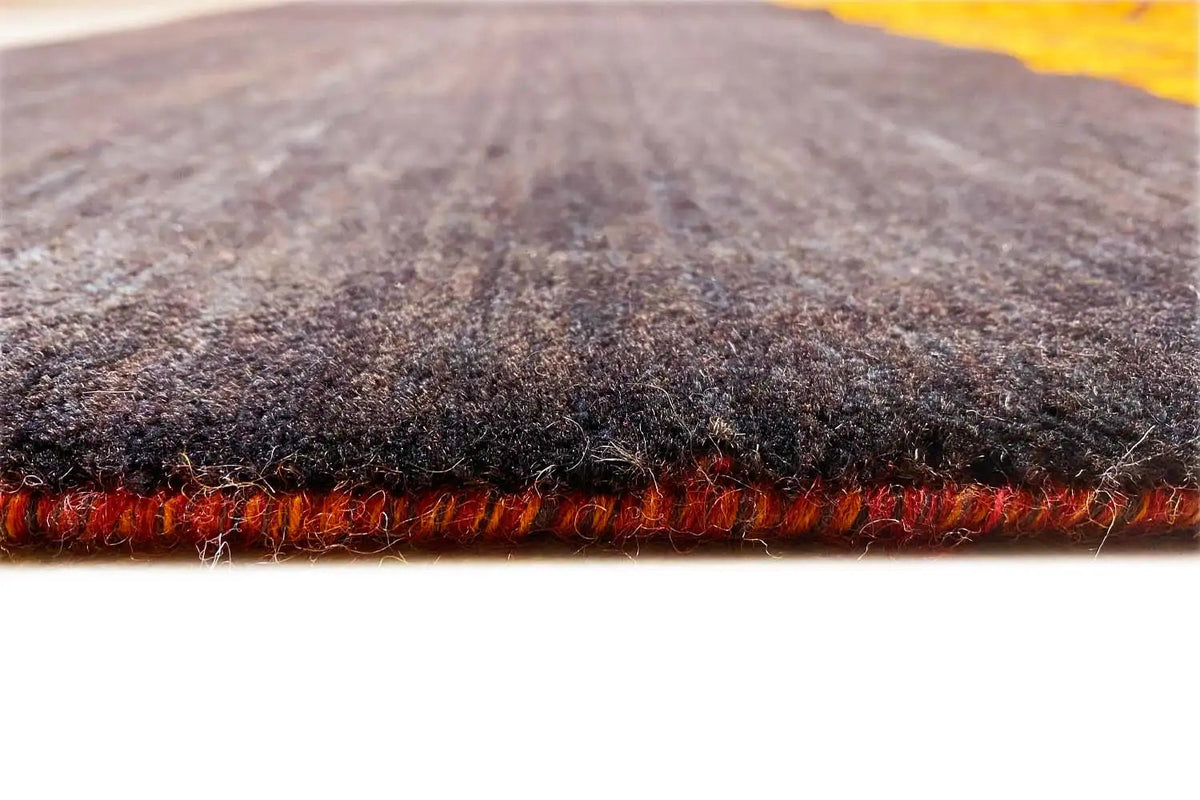 Gabbeh rug close-up: deep-pile edge with fringe, dark gray weave