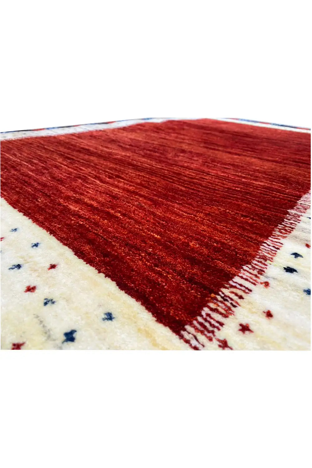 Gabbeh rug detail, red pile with a beige border and small blue star patterns