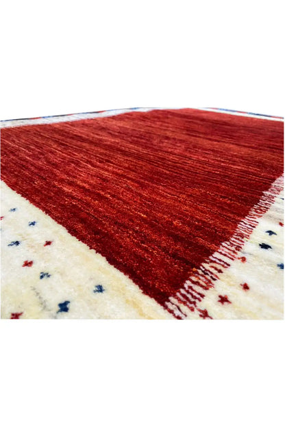 Gabbeh rug detail, red pile with a beige border and small blue star patterns