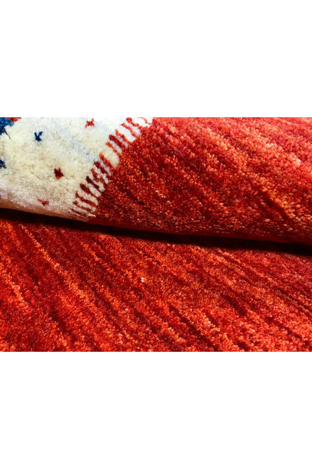 Gabbeh rug detail, red pile with a rolled edge and white seam area