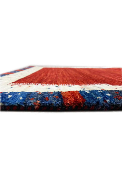 Gabbeh rug edge view, reddish-brown surface with a blue stripe and beige border