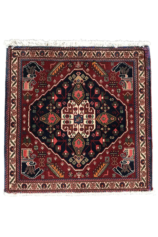 Square rug with a central medallion, dark background, colorful borders, and fringe