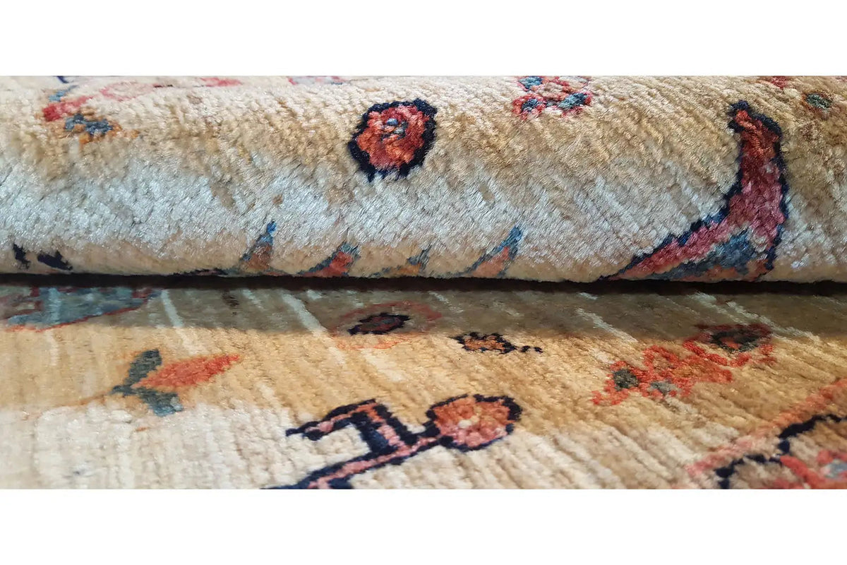 Rug with patterned motifs, beige pile, and colorful border details, close-up