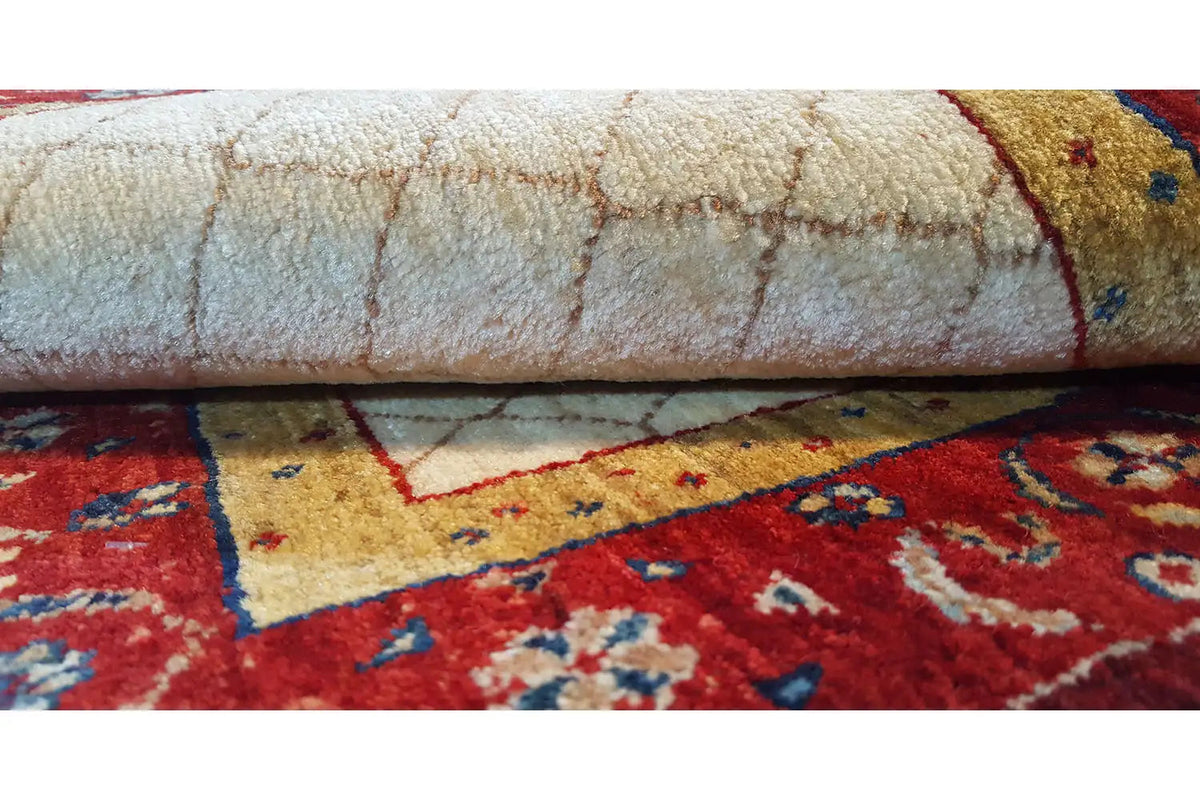Carpet edge with a red border stripe and beige pile, close-up detail view.