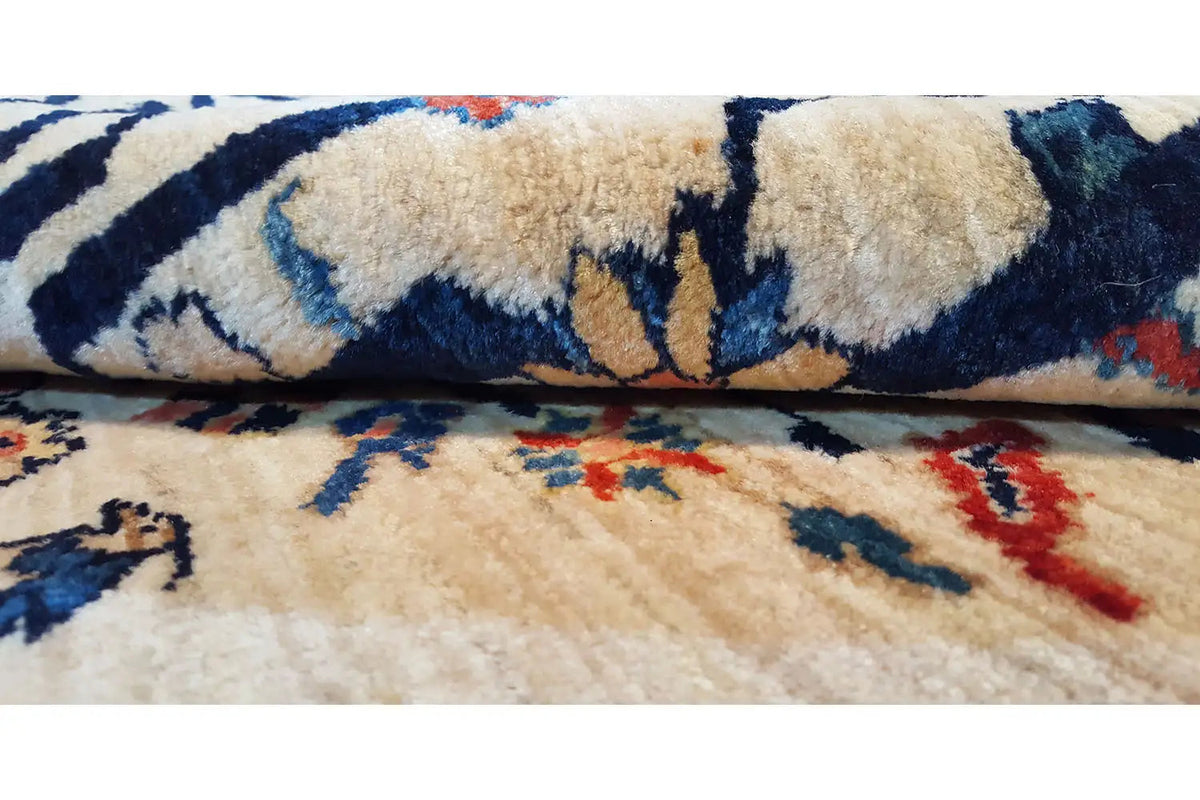 Oriental rug with a blue vine pattern and beige pile texture, close-up