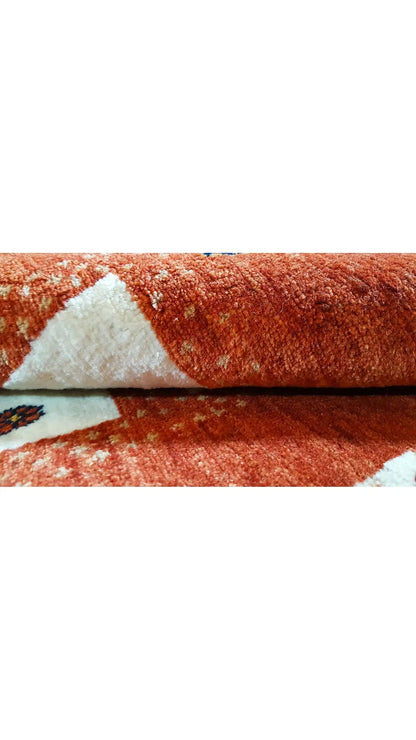 Reddish-brown carpet with a cream-colored pattern and border, close-up of the surface.