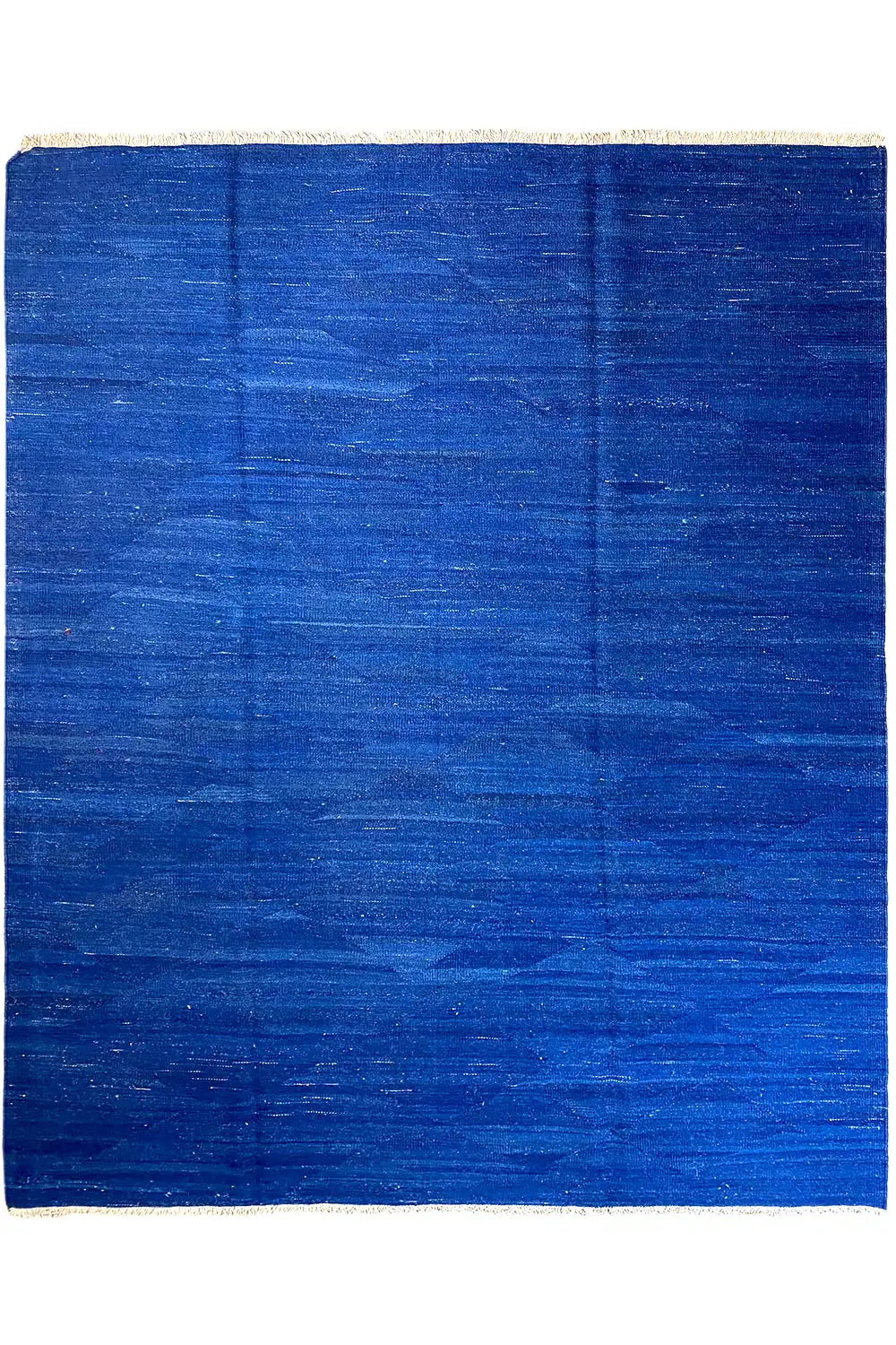 Blue kilim rug with an even pattern and beige border, straight-on view