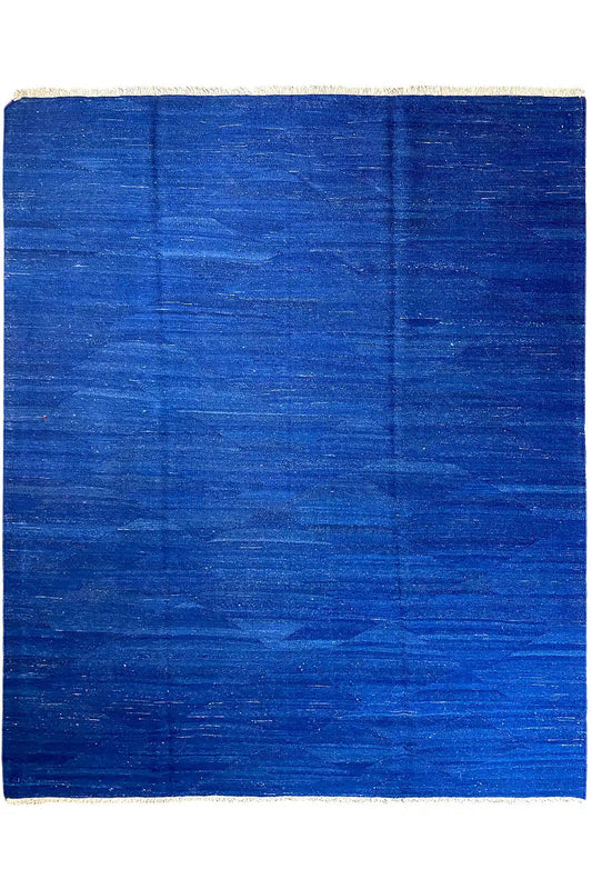 Blue kilim rug with an even pattern and beige border, straight-on view