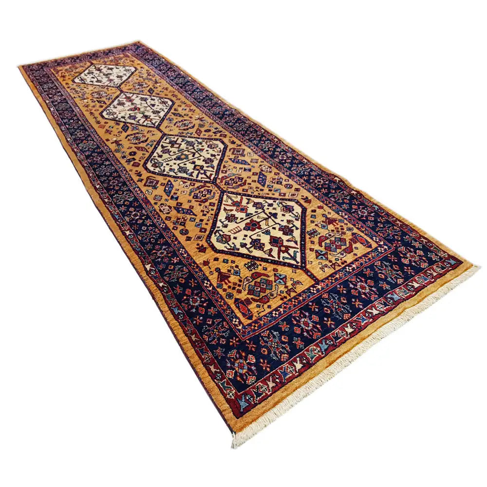 Runner rug in angled view with large diamond motifs in gold, dark blue, and red