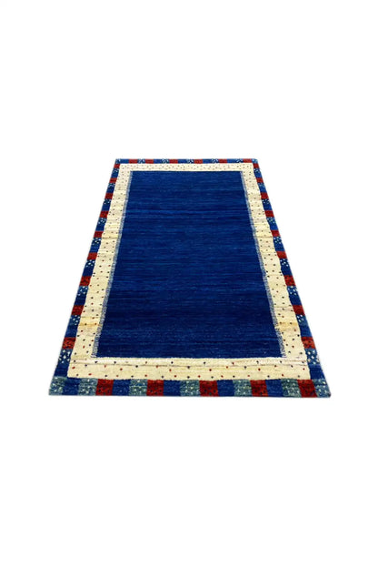 Gabbeh rug with a rectangular blue central field, cream border, and multicolored edge