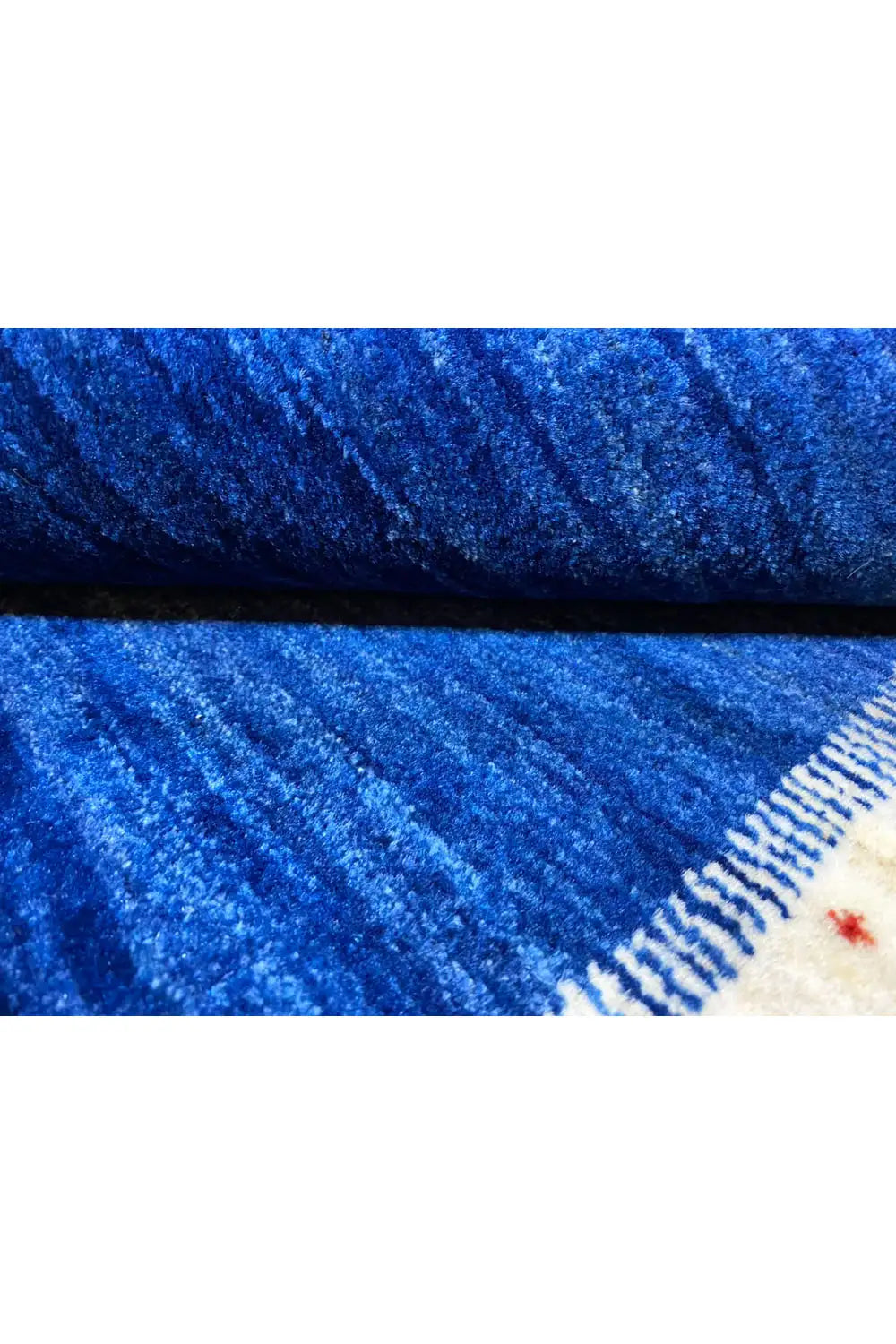 Gabbeh rug detail: blue-mottled pile with a cream-colored edge border