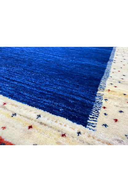 Close-up of a Gabbeh rug: blue weave, cream border with fine red-blue dots