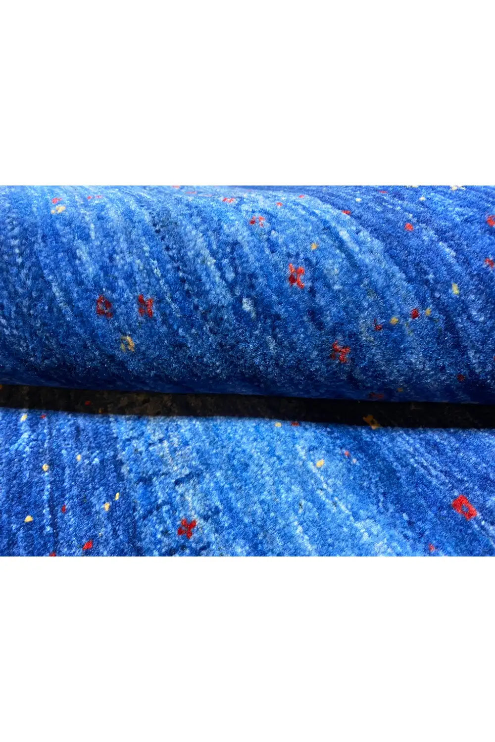 Folded blue Gabbeh rug with a pile edge and colorful flecks
