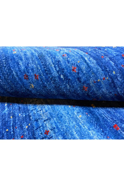 Folded blue Gabbeh rug with a pile edge and colorful flecks