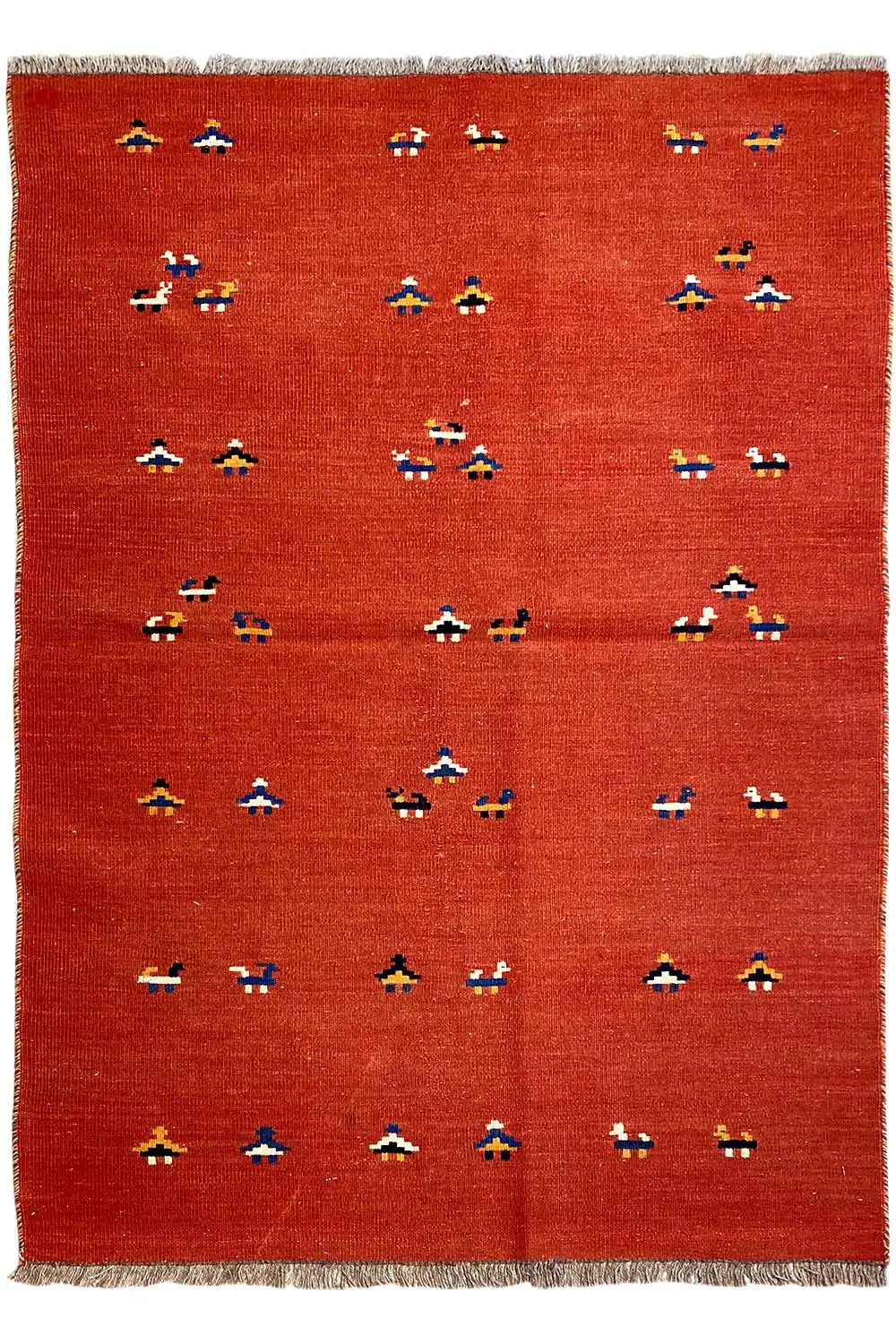 Red kilim rug with rows of small multicolored patterns covering the surface and fringes