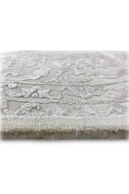 Light beige rug with woven-in ornaments and a short, velvety pile.
