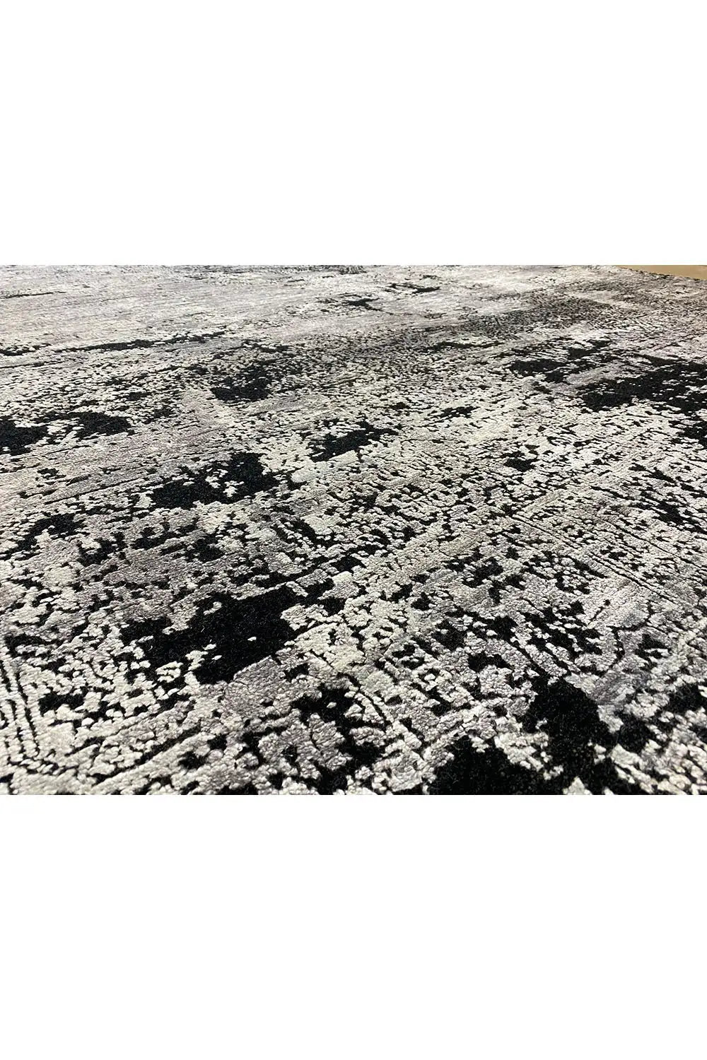Rug with a large-scale abstract black, white and gray pattern, rough pile