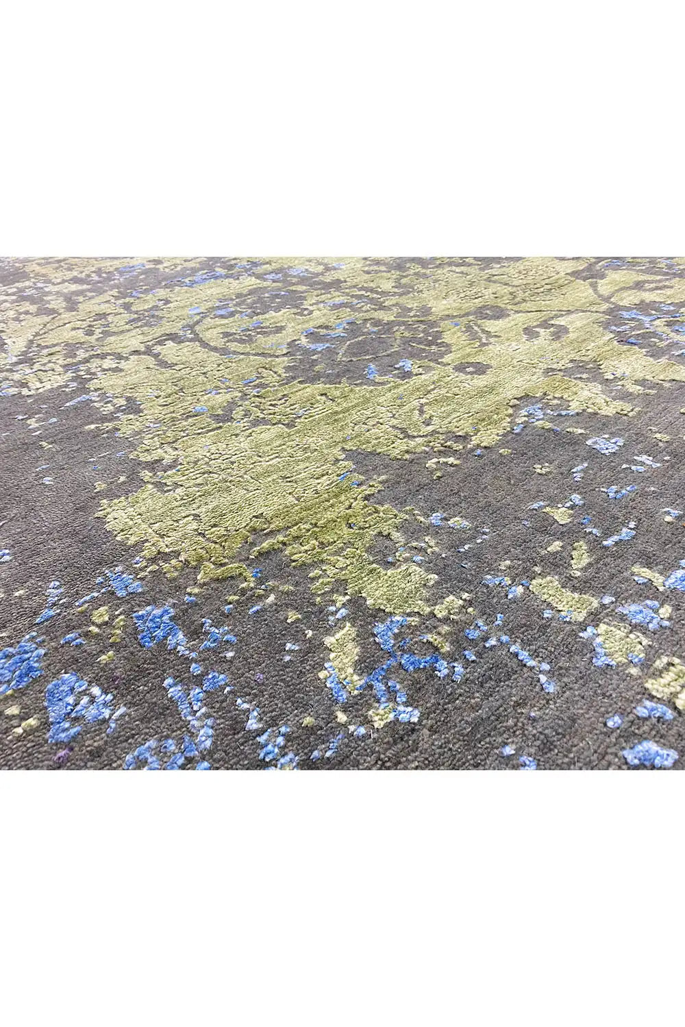 Designer rug with an abstract pattern in green, yellow and blue on a dark background