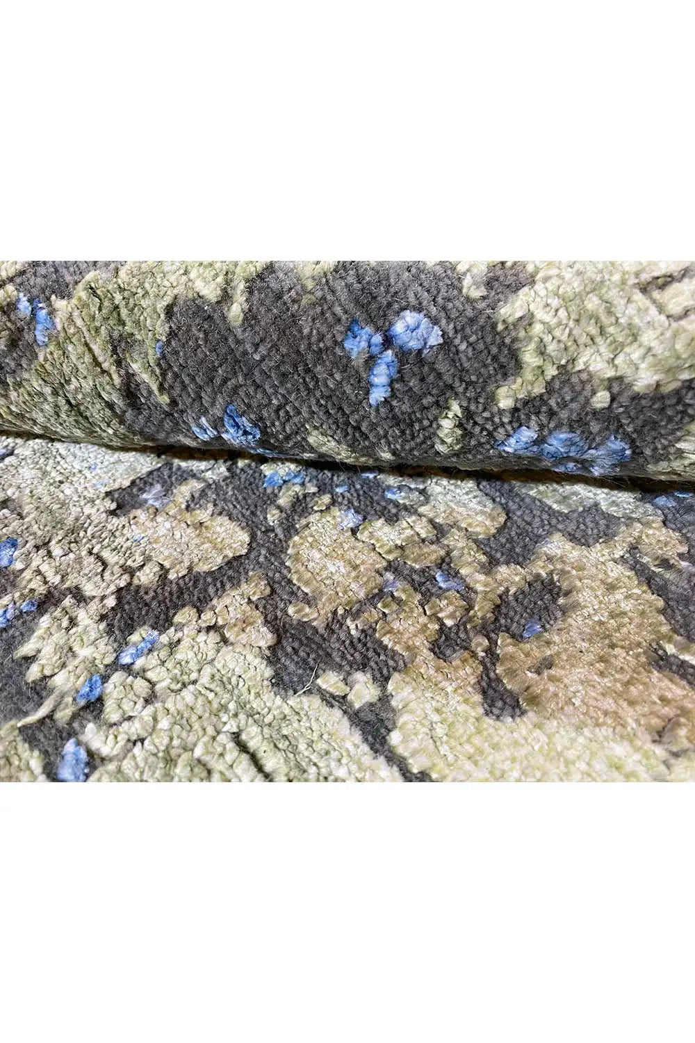 Designer rug close-up: dark gray and blue pattern, green fibers in the pile