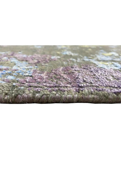 Designer rug viewed from the side: multicolored pile with a purple-brown border