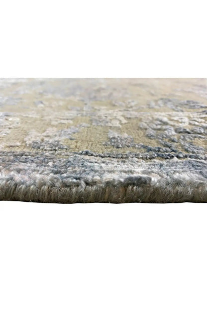 Designer rug edge view: dense pile with blue-gray and cream-colored areas