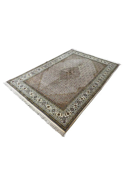 Oriental rug at an angle, brown-beige pile with a geometric border and fringes