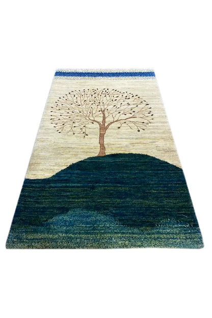 Gabbeh rug with a tree motif on a beige background and dark blue-green hill
