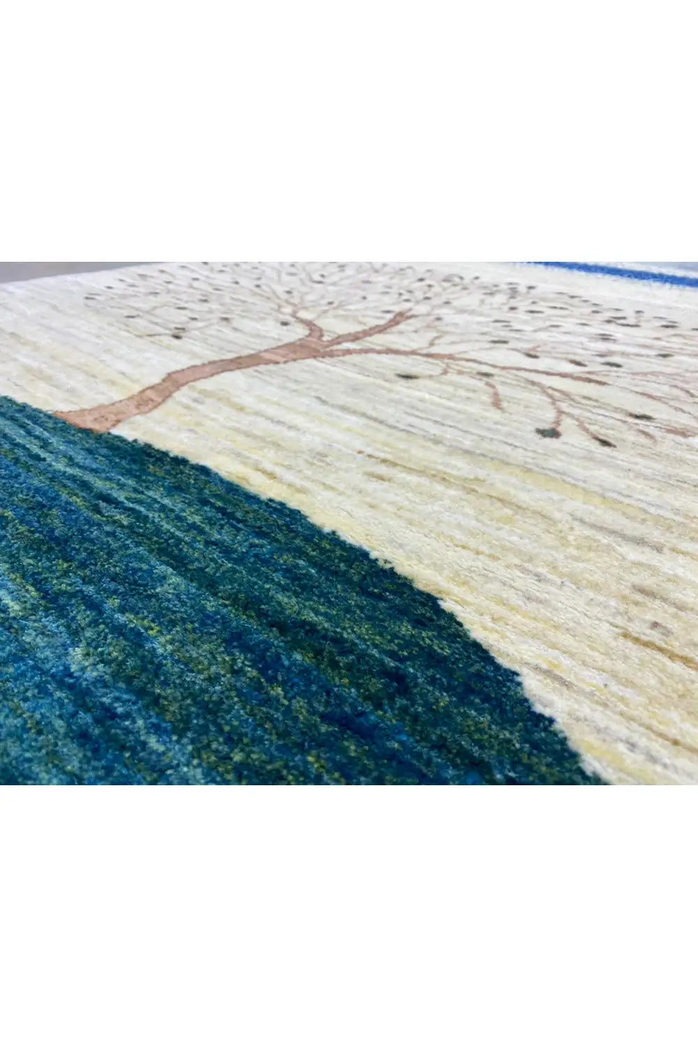 Gabbeh rug close-up: tree motif on a beige background, blue-green hill, border band