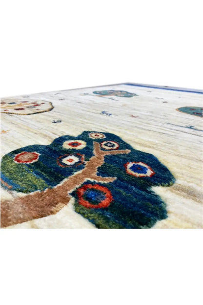 Close-up of 119x75 cm Gabbeh rug: blue tree of flowers with colorful rings on a light background