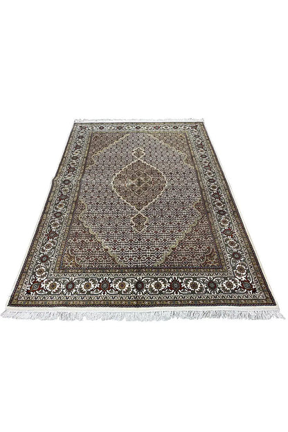 Rectangular rug with a light pattern, dark border, and delicate fringes