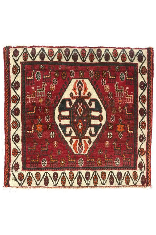 Square rug with a red pattern, white border tape, and fringes