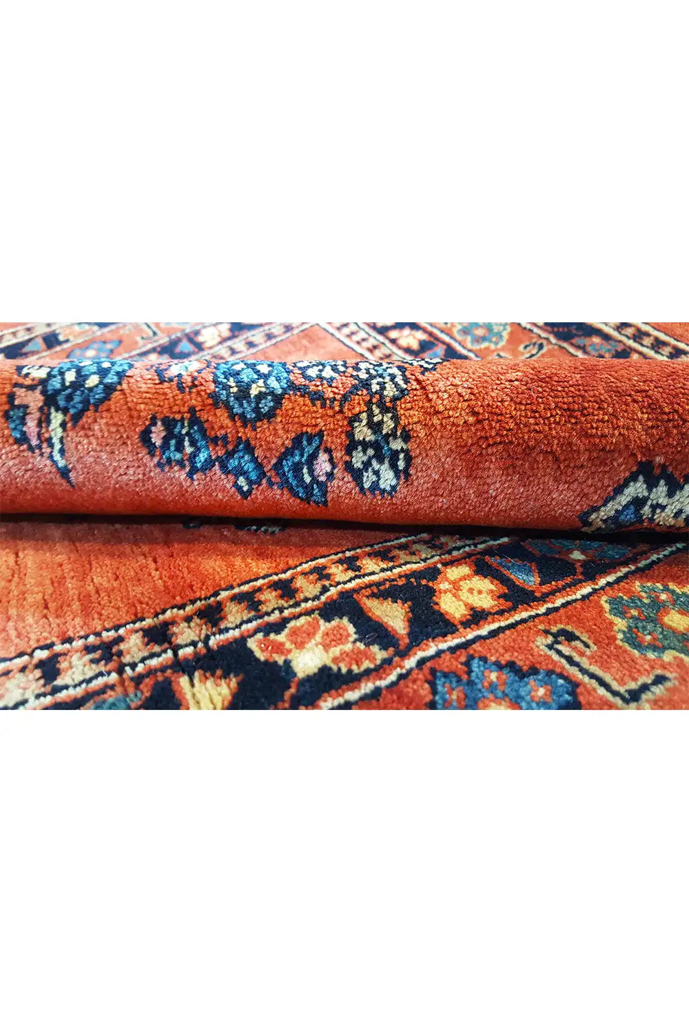 Close-up of carpet pile: red base with blue pattern and finished edge