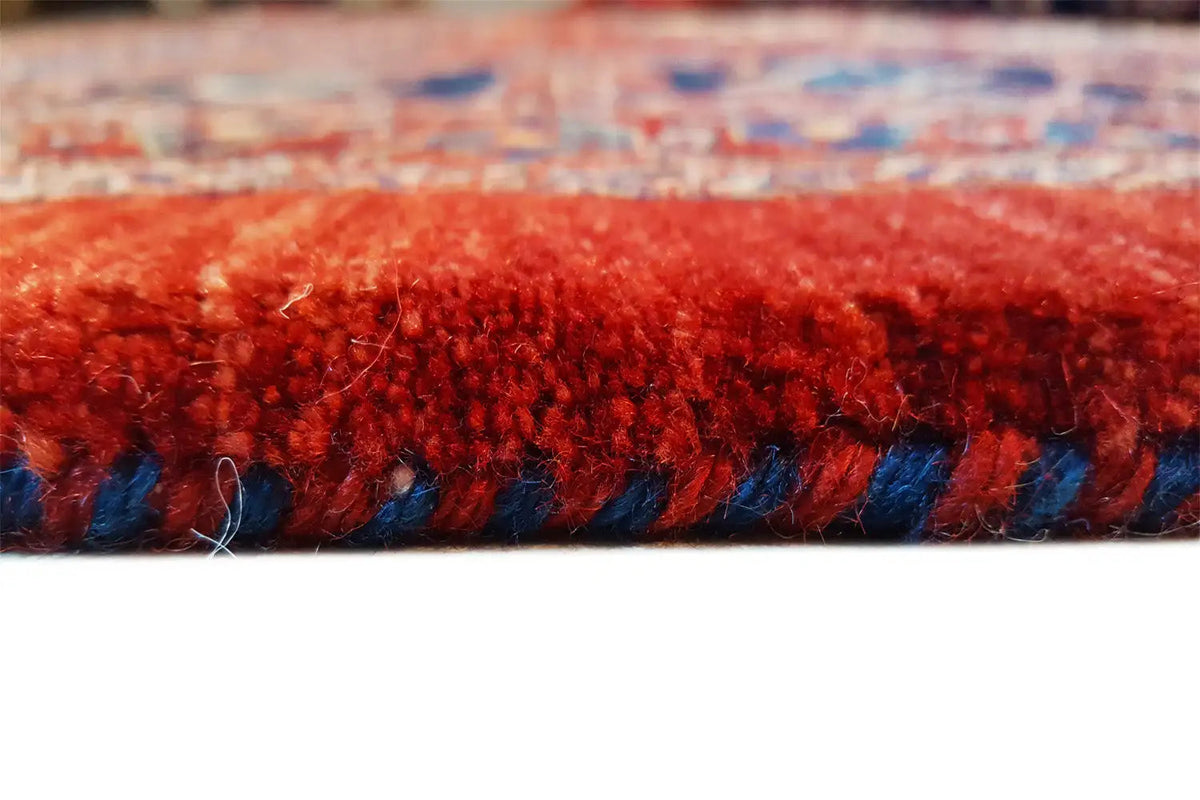 Close-up of the rug edge: red fringes with a blue accent