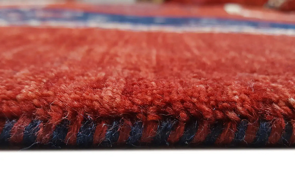 Carpet edge with red pile and a dark blue binding strip, with fringes