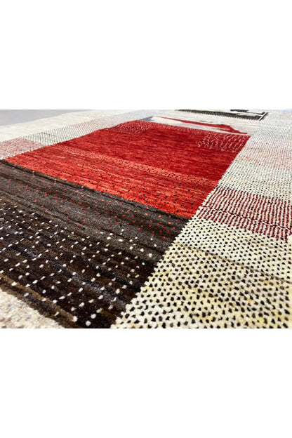 Close-up of a Gabbeh rug: red square, black dotted area, and beige border with stripes