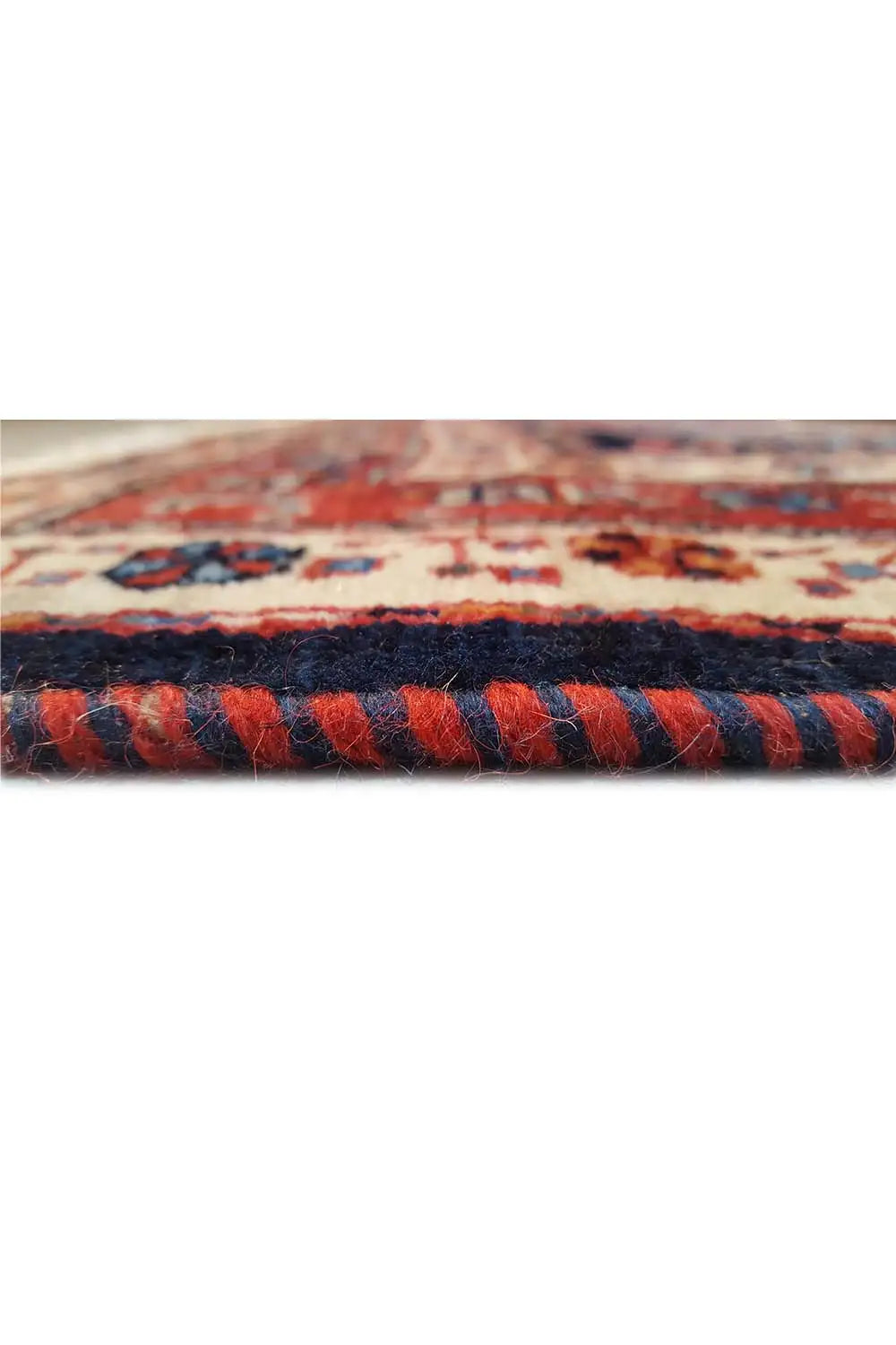 Close-up: carpet edge with dense, multicolored pile and woven border pattern