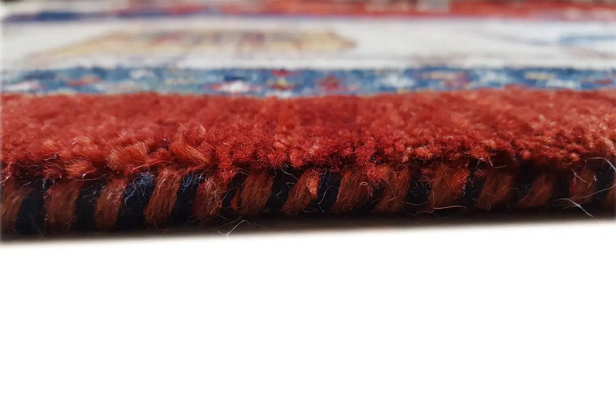 Close-up of a rug edge with a dense fringe border in red and dark blue