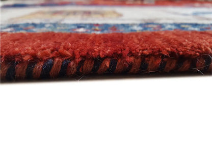 Close-up of a rug edge with a dense fringe border in red and dark blue