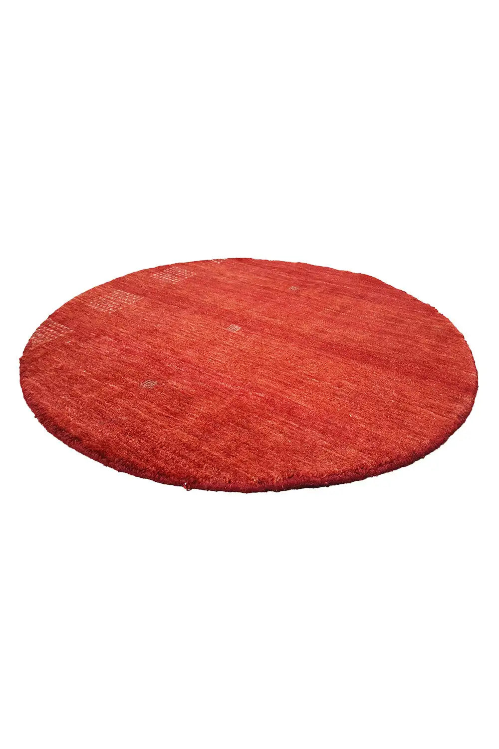 Round “Lori” Gabbeh rug (86x86 cm) in red, lying flat viewed from an oblique angle