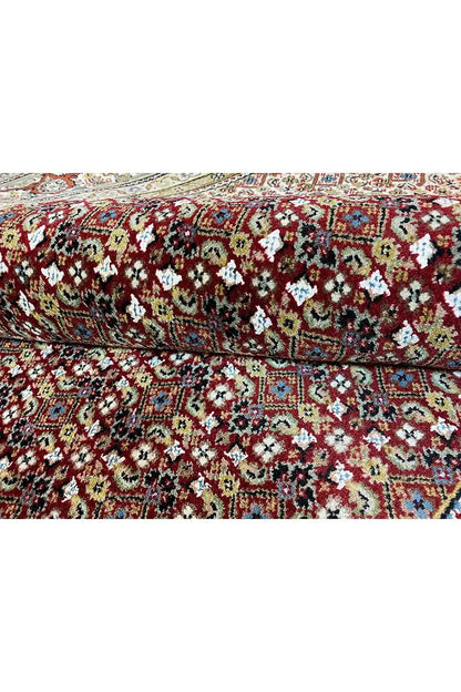 Rug overlay with a dense pattern in red, green, and beige, decorative floral ornaments