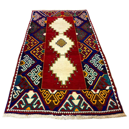 Gabbeh rug: three cream medallions on a red field, blue zigzag border, fringes