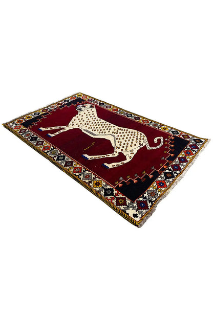 Gabbeh rug, shown at an angle: animal motif in beige on dark red, with an ornamental border